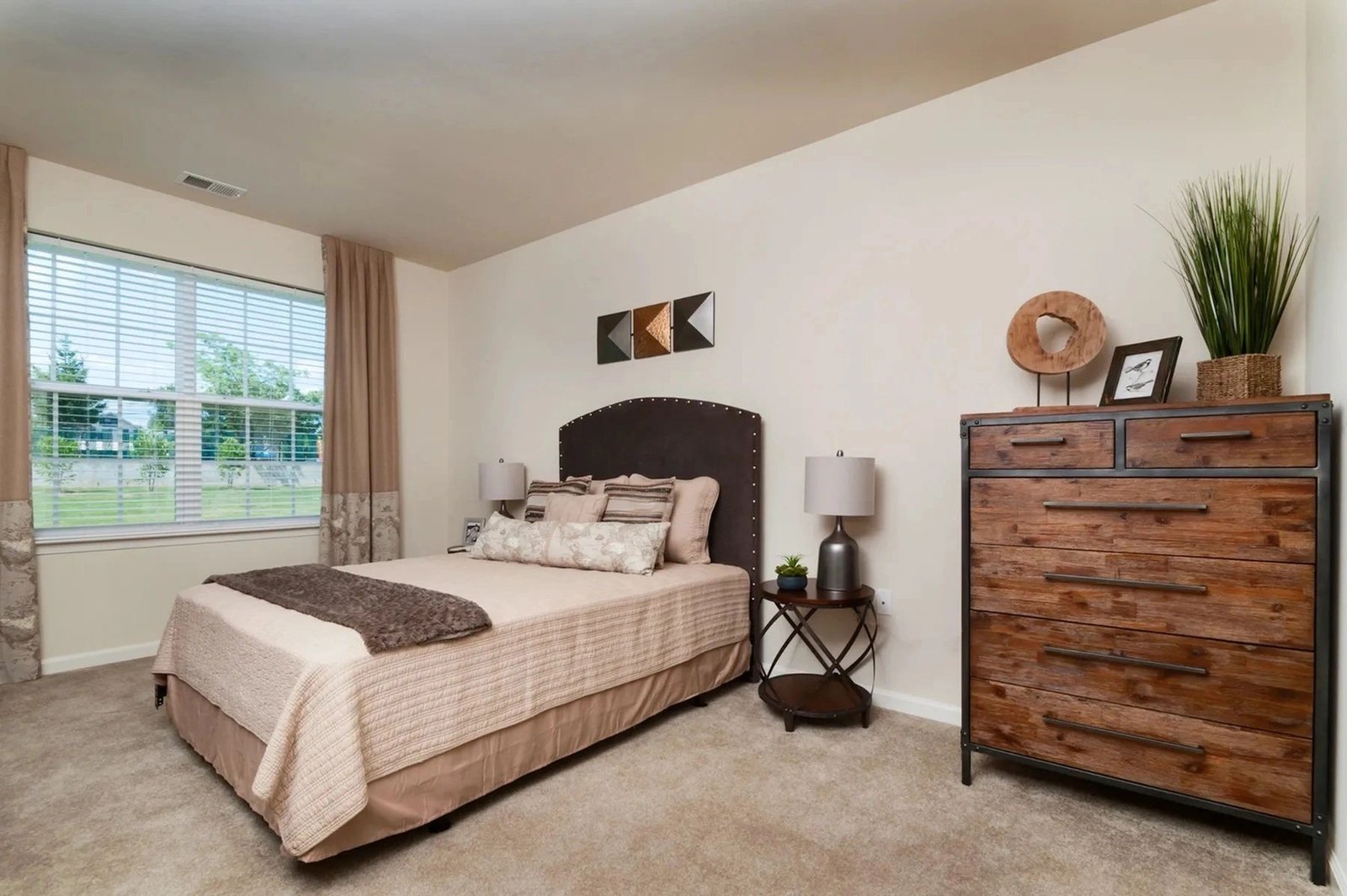A warmly staged model-apartment bedroom.